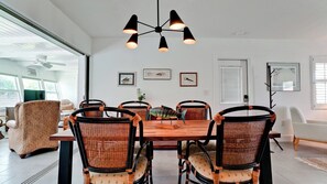 A dining area with a wooden table, wicker chairs, and a modern pendant light.