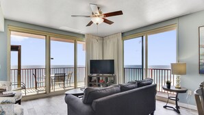 A living room with a sofa, TV, and balcony with a view. - Incredible Views from the 22nd Floor! Free Activities + Summer Deals! (Panama City Beach)