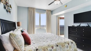 A bedroom with a bed, a ceiling fan, a dresser, a TV, and a view of the outdoors. - Incredible Views from the 22nd Floor! Free Activities + Summer Deals! (Panama City Beach)