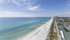 An aerial view of a beachside hotel with a long, narrow building along the shoreline, featuring a series of balconies and a clear view of the ocean. - Incredible Views from the 22nd Floor! Free Activities + Summer Deals! (Panama City Beach)