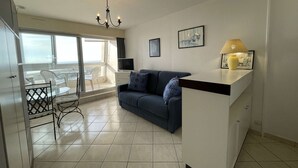 A modern living room with a sofa, a TV, and a balcony with a table and chairs.