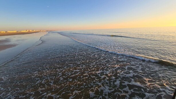 A beach with gentle waves and a clear sky.