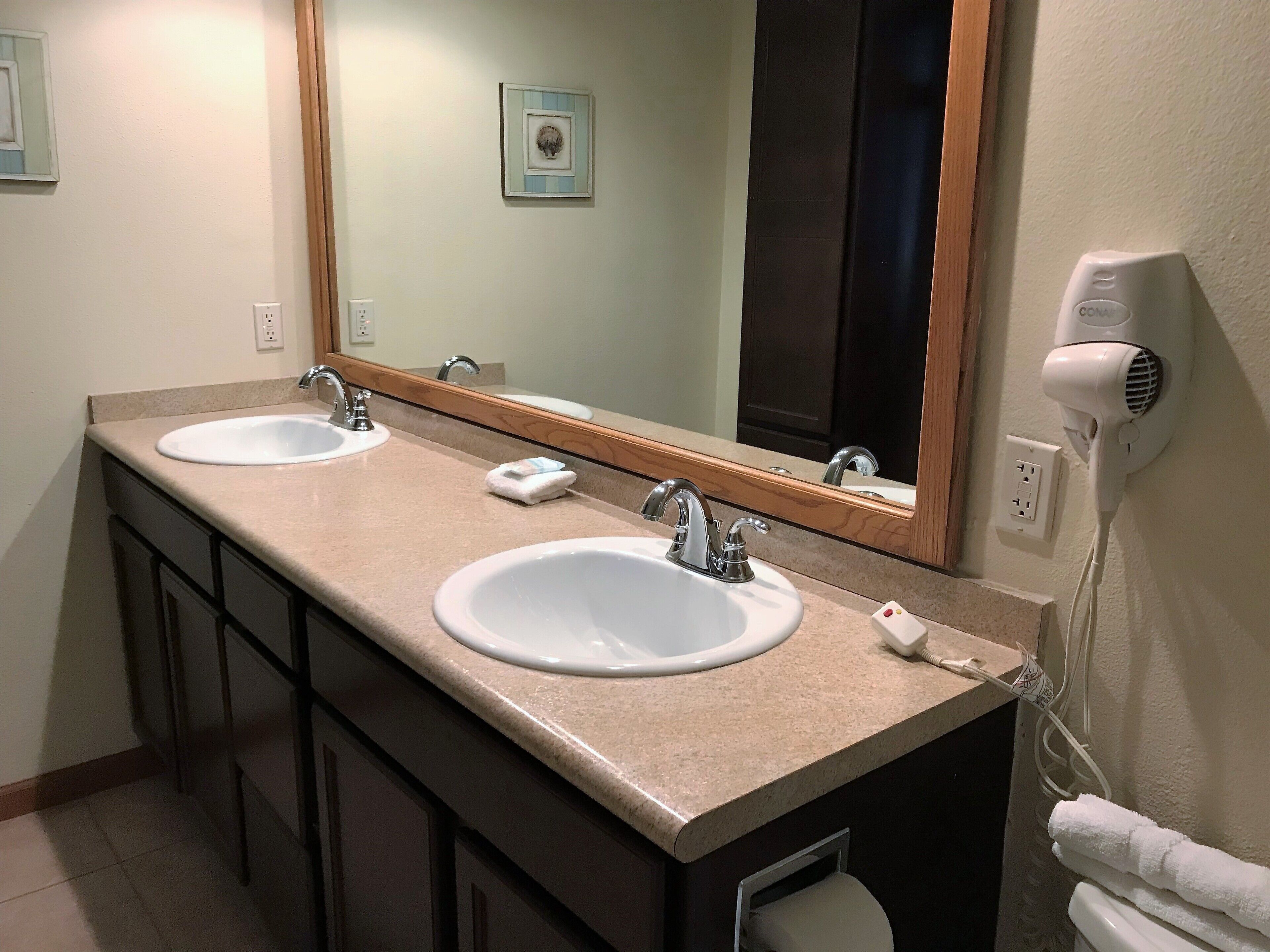 A bathroom with two sinks, a mirror, a towel rack, and a hair dryer.