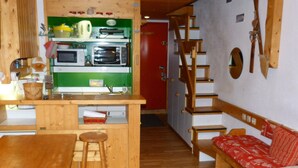 Eine kleine Küche mit einer Holz-Kochinsel, einem Esstisch und einem roten Sofa.