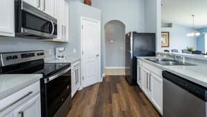 Una cucina moderna con mobili bianchi, elettrodomestici in acciaio inossidabile e pavimento in legno.