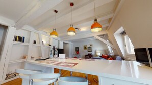 A modern kitchen with white cabinetry, a central island with bar stools, and pendant lighting.