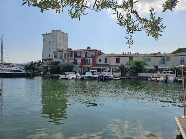 Un puerto deportivo con barcos amarrados, un edificio de torres y casas coloridas a lo largo del muelle.