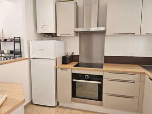 Eine kompakte Küche mit Backofen, Geschirrspüler und Kühlschrank.