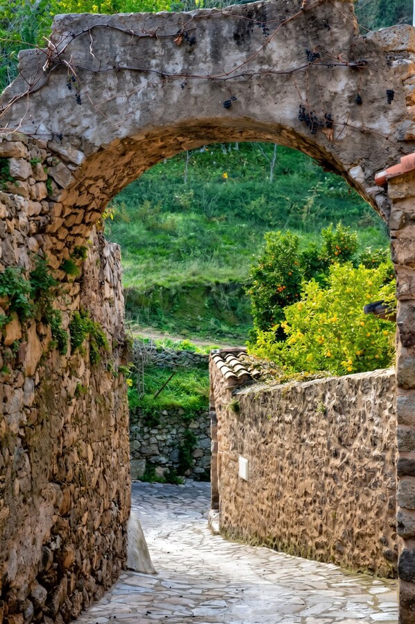 A stone archway leading to a stone pathway surrounded by greenery.