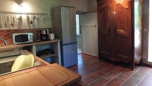 A kitchen with a wooden cabinet, a refrigerator, a microwave, and a sink. - Homerez - Flat in Feliceto (Feliceto)