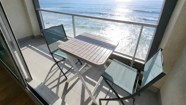 A balcony with a table and two chairs, overlooking the ocean. - Studio with balcony, WIFI, and parking near the beach (Les Sables-d'Olonne)