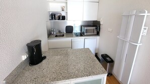 A compact kitchenette with a microwave, coffee maker, and a small sink. - Studio with balcony, WIFI, and parking near the beach (Les Sables-d'Olonne)