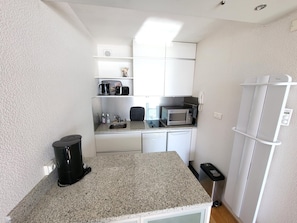A compact kitchenette with a microwave, coffee maker, and a small sink. - Studio with balcony, WIFI, and parking near the beach (Les Sables-d'Olonne)