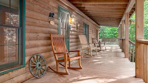A wooden cabin with a porch, rocking chairs, and a welcome sign. - Secluded, Close to Town, Hot Tub, Fire Pit, WiFi, Pets Ok! (Fairview)