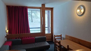 A cozy room with a wooden bench, a small table, and a window with red curtains. - Ski-in/out apartment for 7 guests, pets allowed, Les Arcs 1800 (Les Arcs 1800)