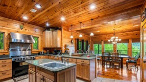 Un'ampia cucina con mobili in legno, un'isola grande e una zona pranzo con vista sull'esterno.