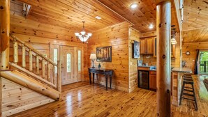 Interno di una baita in legno con una scala, una zona pranzo e una cucina.