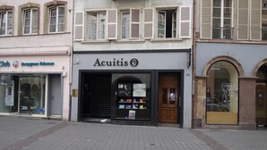 A storefront with a sign reading "Acuitis" and a closed shutter door.
