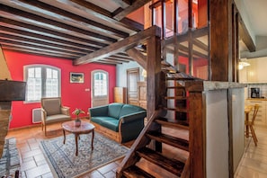 A cozy living room with a staircase, wooden beams, a green sofa, and a small table with a plant. - Homerez - House in Bangor (Bangor)