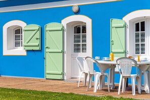 A building with a blue exterior, white trim, and green shutters. There is a table with chairs and a bottle of orange juice. - Homerez - House in Bangor (Bangor)