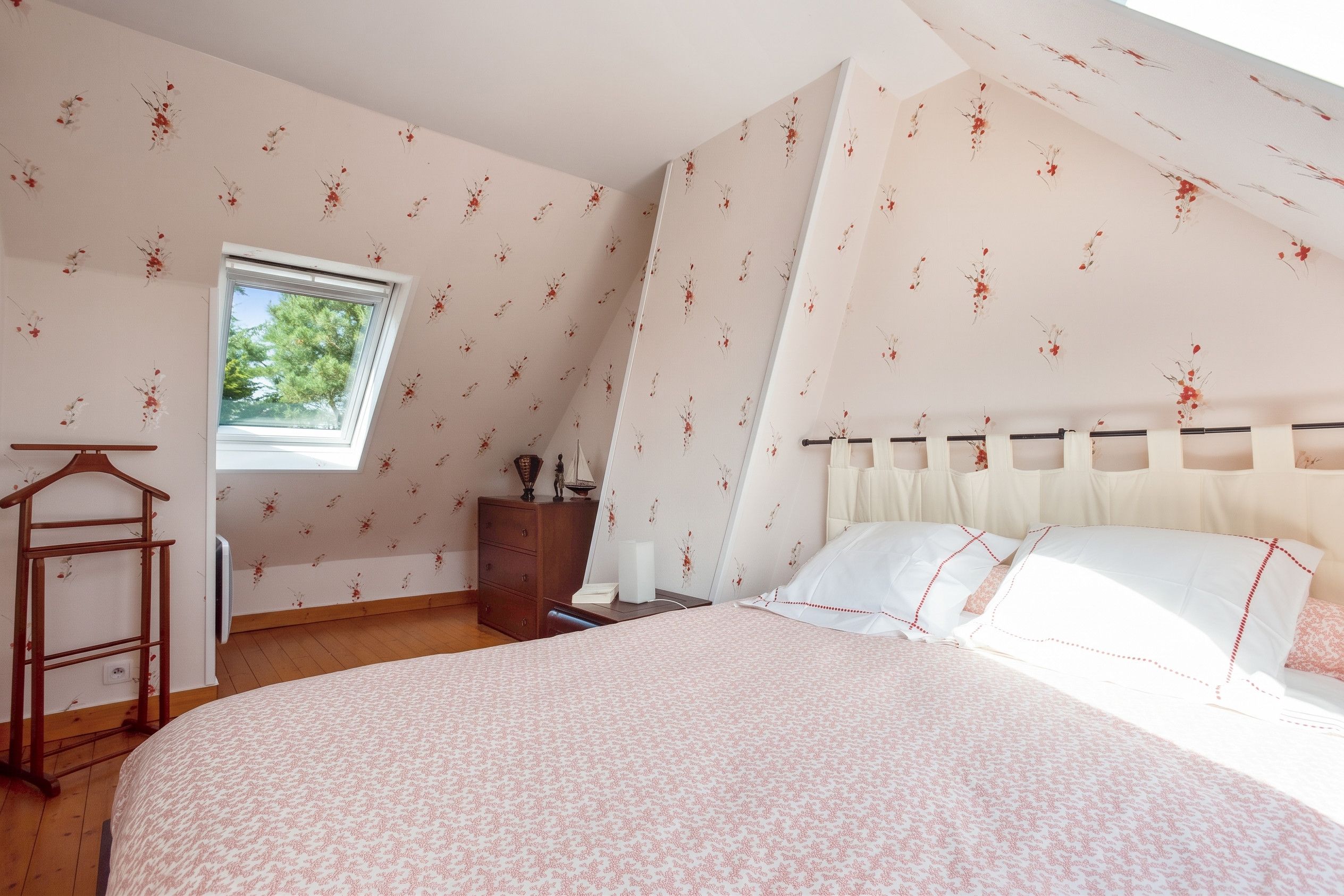A bedroom with a bed, a dresser, a window, and a wooden ladder.