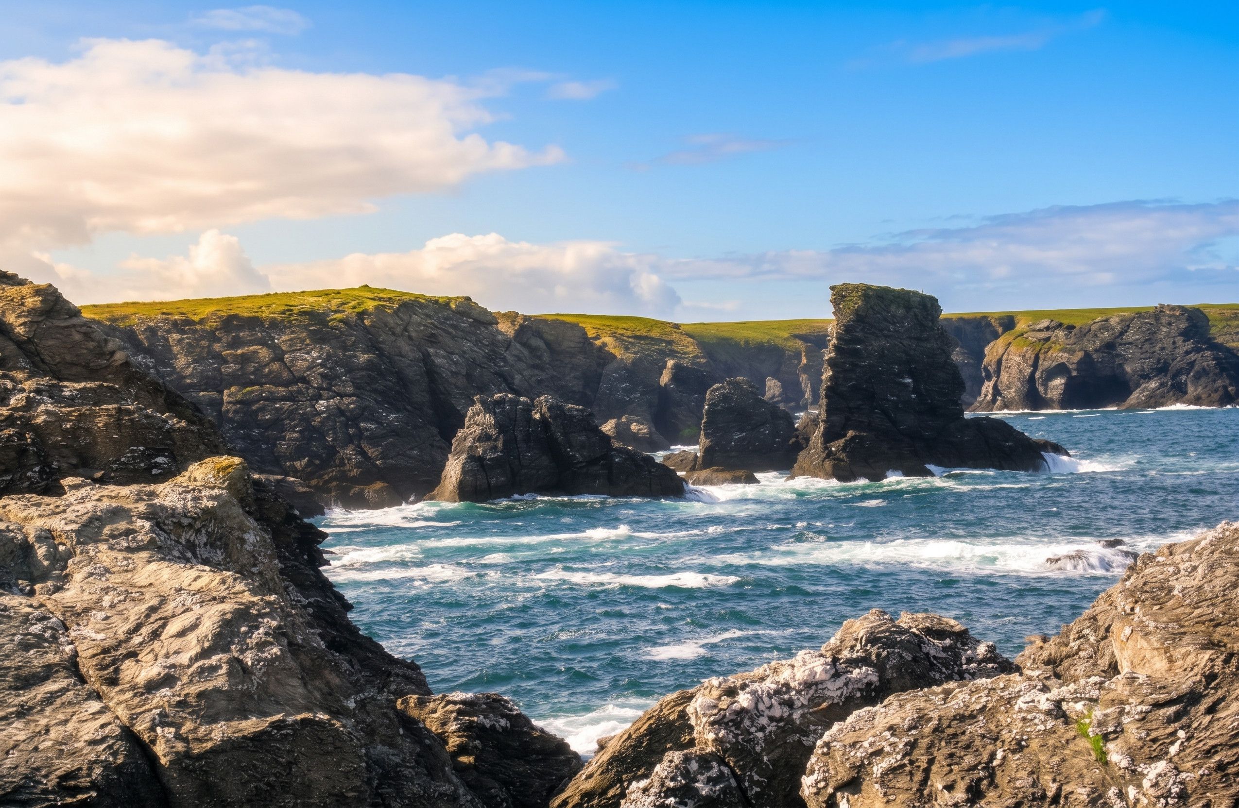 Un paisaje costero con acantilados rocosos y olas rompiendo contra ellos.
