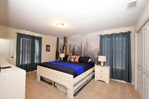 A bedroom with a bed, nightstands, a dresser, and a cityscape mural on the wall.