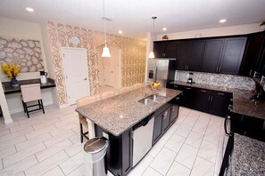 A modern kitchen with granite countertops, stainless steel appliances, and dark cabinetry.