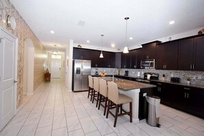 A modern kitchen with dark cabinetry, a stainless steel refrigerator, a microwave, and a granite countertop.
