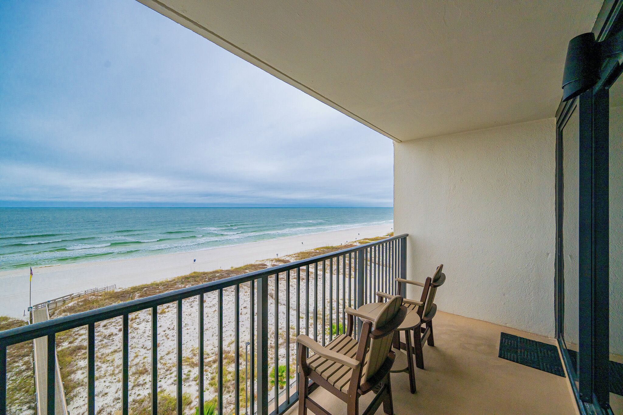 A balcony with a view of the beach and ocean.