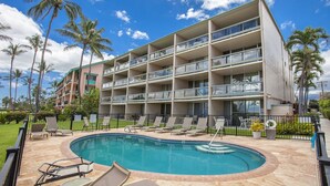 A hotel with a pool, multiple balconies, and palm trees.