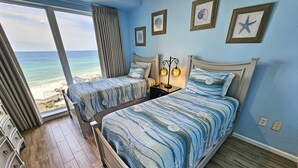 Een slaapkamer met twee bedden, uitzicht op de oceaan en een nautisch thema.
