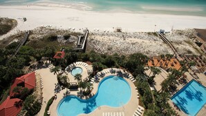 Luchtbeeld van een resort met een groot zwembad, een strand en een uitkijktoren voor de badmeester.