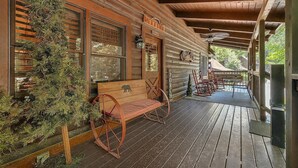 A wooden cabin with a porch, a rocking chair, and a bench. - ER258- Sweet Memories Great location- Close to town (Pigeon Forge)
