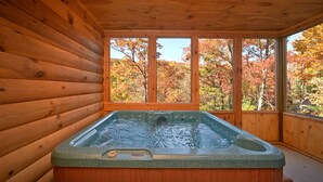 A hot tub in a wooden cabin with large windows overlooking autumn foliage. - A Secret Hideaway: Pool Table, Convenient, Value (Sevierville)