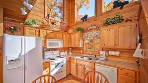 A wooden cabin kitchen with a refrigerator, stove, microwave, sink, and dishwasher. - A Secret Hideaway: Pool Table, Convenient, Value (Sevierville)