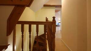 A wooden staircase leading to a bedroom with a bed and a nightstand. - Bright countryside house with garden and fireplace (Saint-Jean-de-Savigny)