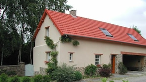 A two-story house with a red roof, a stone foundation, and a garage. - Bright countryside house with garden and fireplace (Saint-Jean-de-Savigny)