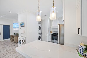 A modern kitchen with a marble countertop, a washing machine, and a dining area with a large island.