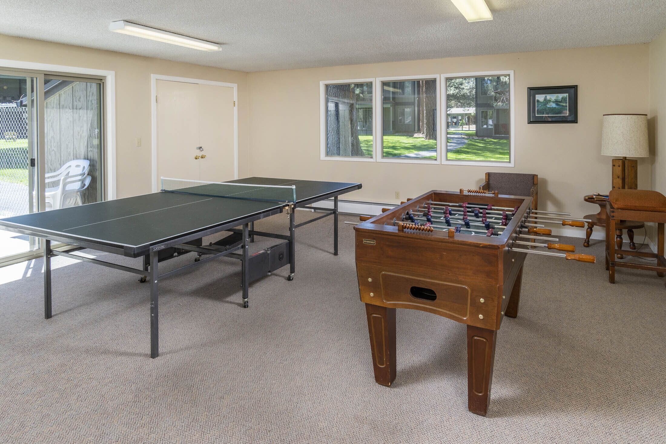 Um quarto com mesa de pingue-pongue, mesa de futebol de mesa e uma porta que dá para um pátio com área de estar ao ar livre.