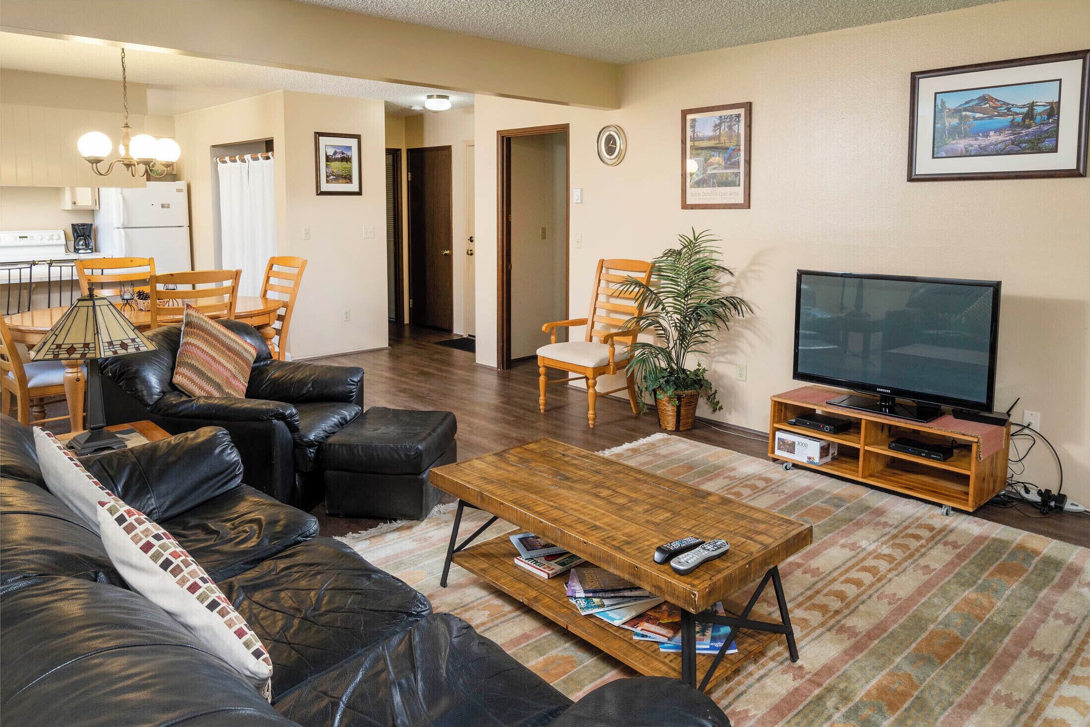 A living room with a leather sofa, a wooden coffee table, a television, and a dining area with a table and chairs.