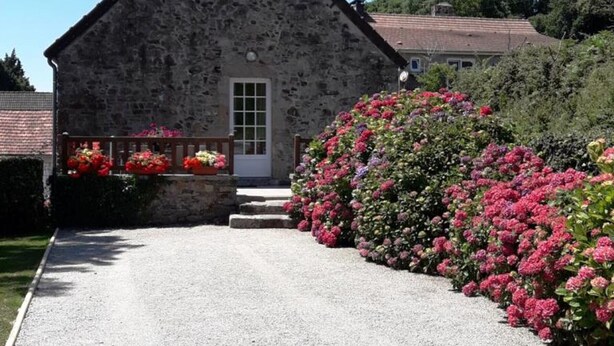 A stone building with a gabled roof, a front door, and a gravel driveway leading to a porch with flower boxes. - Holiday home 4 pers, private garden, in La Hague (Vasteville)