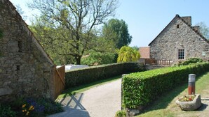 A stone building with a gravel path leading to a wooden gate. - Holiday home 4 pers, private garden, in La Hague (Vasteville)