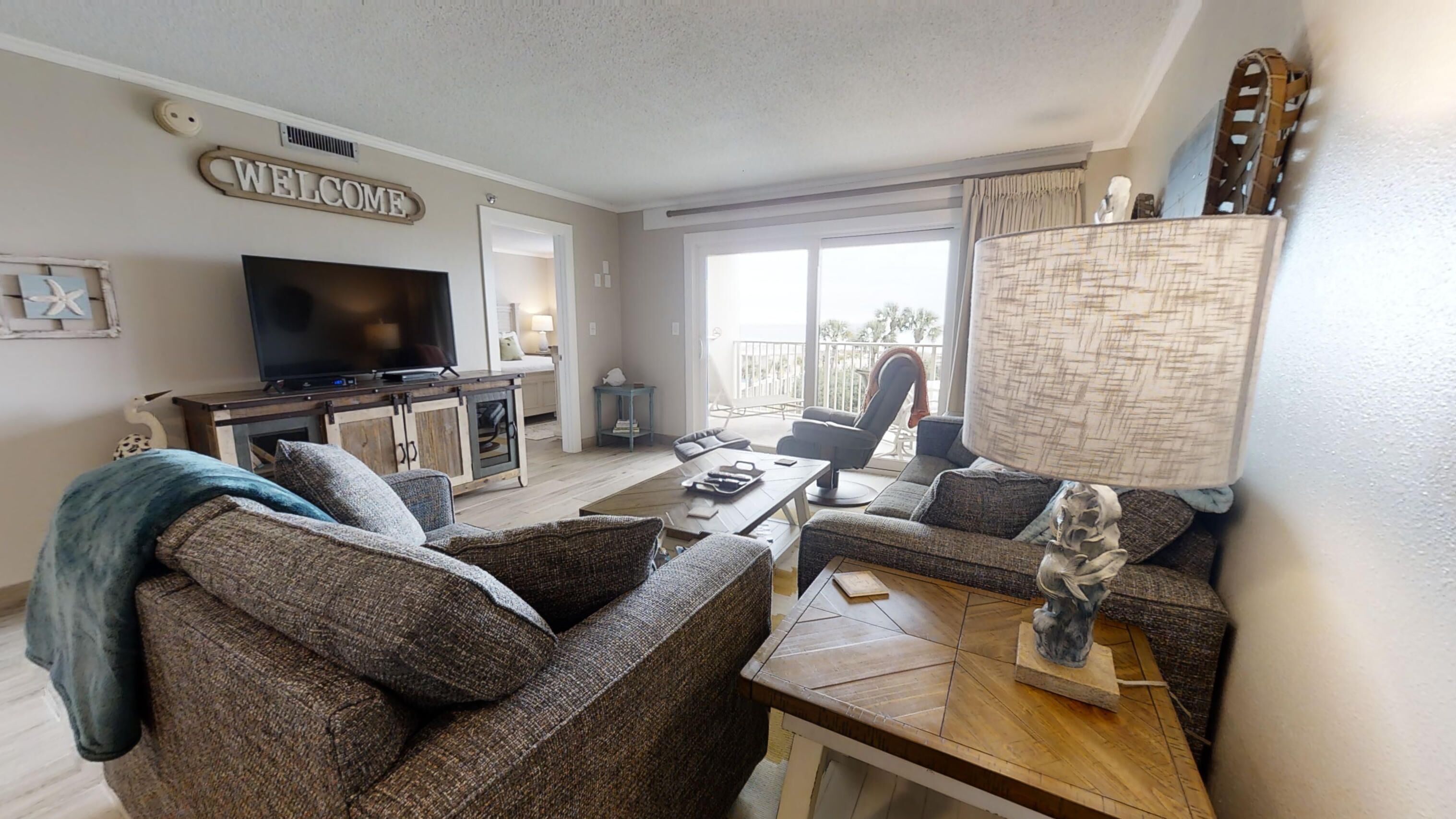 A living room with a television, sofas, a coffee table, and a balcony with a view.