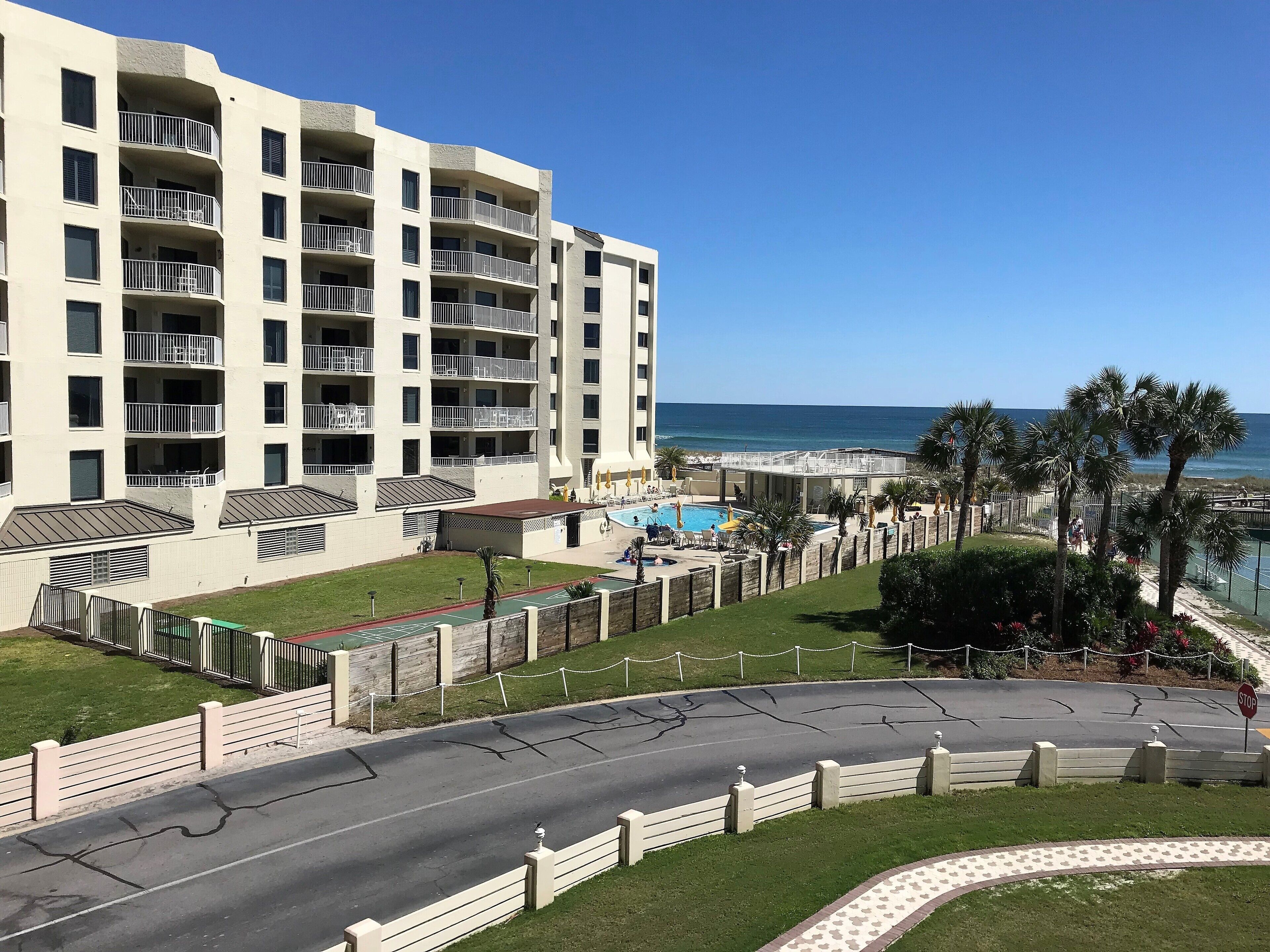 Un hotel de varios pisos con balcones, piscina y vista al océano.