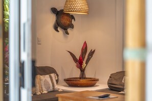 Una habitación con decoración de tortuga en la pared, un jarrón con flores rojas, una mesa de madera y un sofá con cojines.