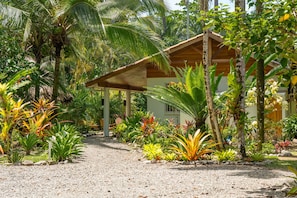 A tropical resort with a covered outdoor seating area, lush vegetation, and a gravel path. - Our Bungalow Punta Uva • 3BR Beachfront with A/C (Punta Uva)
