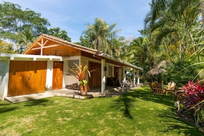 A house with a wooden exterior, a thatched roof, and a well-maintained lawn. - Our Bungalow Punta Uva • 3BR Beachfront with A/C (Punta Uva)