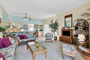 A living room with a sofa, armchairs, a coffee table, and a television.