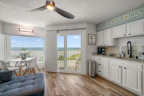 A modern kitchen with white cabinets, a coffee maker, and a trash can.